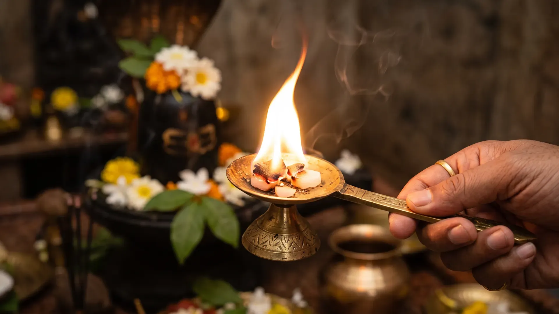 Camphor burning in a brass aarti holder before a Shivling